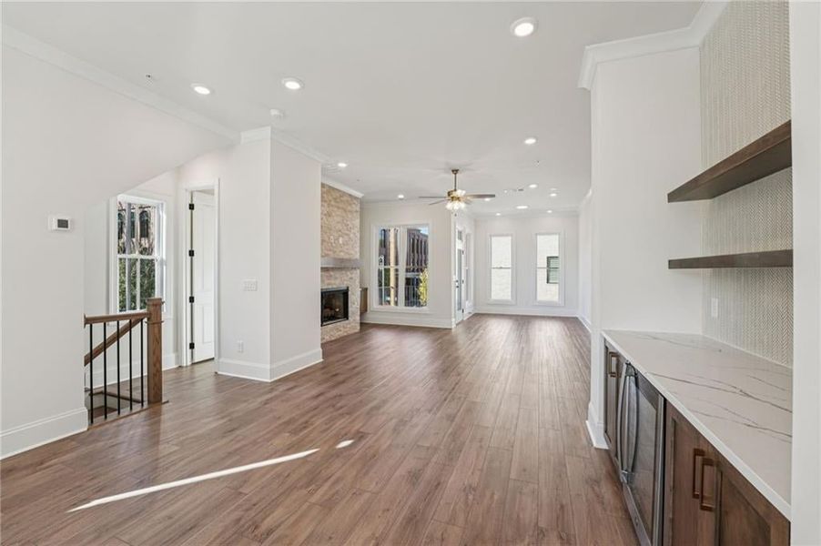 Family/living room space flows open from the kitchen and dining area- elevated finishes like bar area aiwth beverage cooler with matching Quartz top to the oversized Kitchen Island, floating shelves and decorative tile detail finish off this space.