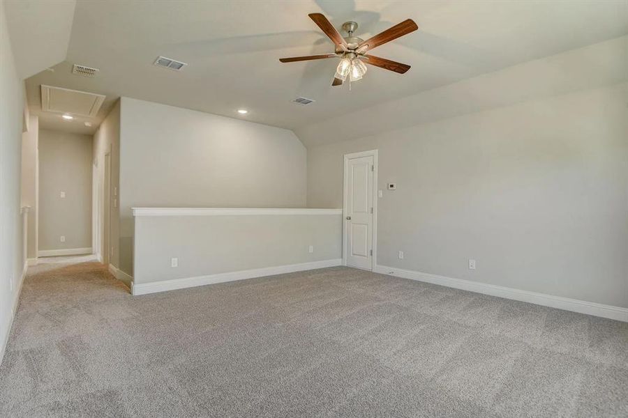Empty room featuring vaulted ceiling, ceiling fan, light colored carpet, attic access, and recessed lighting