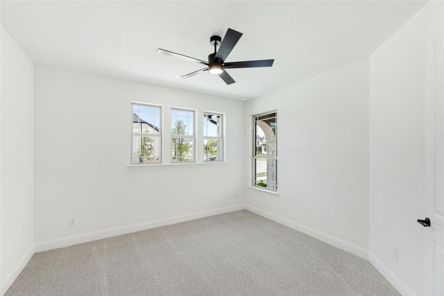 Empty bedroom with white walls, carpet flooring, ceiling fan, and multiple windows Empty bedroom with white walls, carpet flooring, ceiling fan, and multiple windows