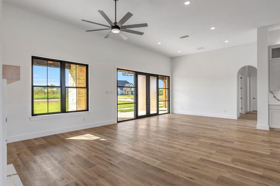 Living room with arched walkways, recessed lighting, light wood finished floors, a ceiling fan, and custom iron and glass sliding door.