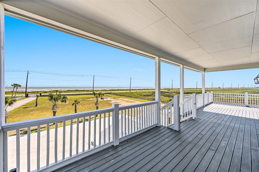 This spacious covered deck flows seamlessly to the pool and entertaining areas below. Whether gathering with friends or enjoying quiet moments, the setting was designed for coastal living.