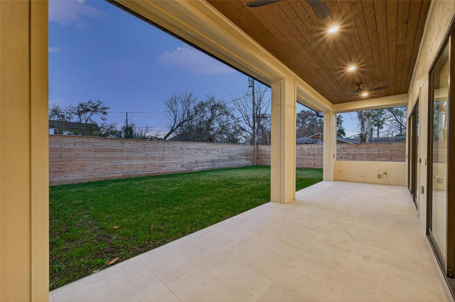 Covered patio with wood ceiling, recessed lighting, and dual fans. Summer kitchen ready!