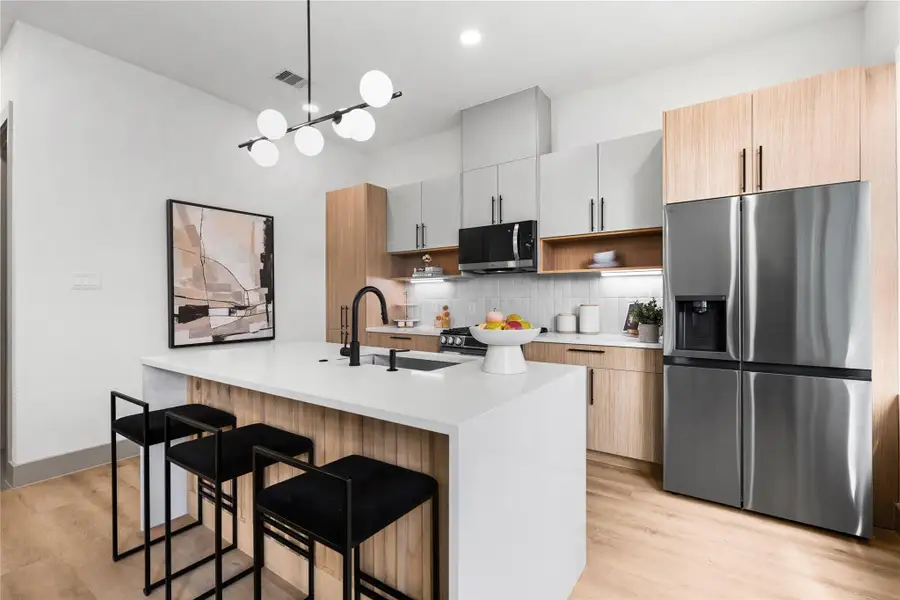 This statement island does it all—prep, serve, sip your morning coffee or gather with friends. Wrapped in a waterfall quartz slab with slatted wood detail and matte black fixtures, it's where everyday routines feel a little more luxurious. This statement island does it all—prep, serve, sip your morning coffee or gather with friends. Wrapped in a waterfall quartz slab with slatted wood detail and matte black fixtures, it's where everyday routines feel a little more luxurious.