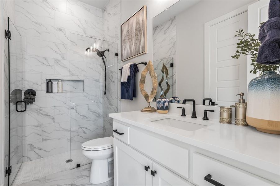 Secondary bathroom with frameless glass shower, upgraded tile and a shampoo nook