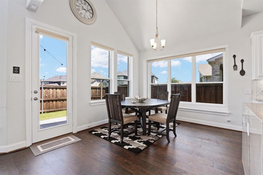 Dining room featuring dark hardwood / wood-style floors, vaulted ceiling, and an inviting chandelier