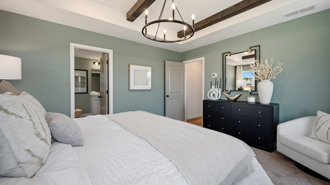Primary bedroom featuring elegant tray ceiling in new construction townhome at Langley Overlook in Loganville, GA.