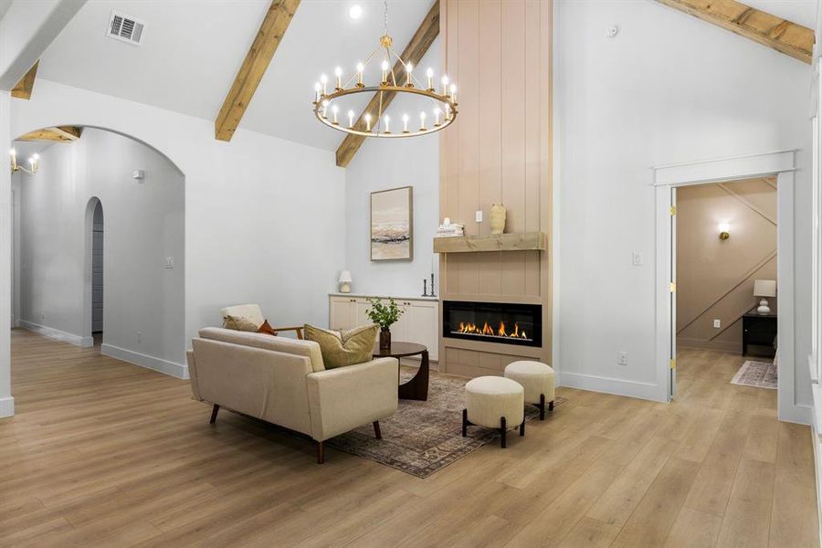 Living room featuring light hardwood / wood-style flooring, beam ceiling, high vaulted ceiling, and a tiled fireplace