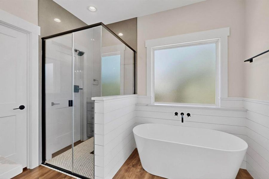 Bathroom with a shower stall, wood finished floors, a freestanding bath, wainscoting, and recessed lighting