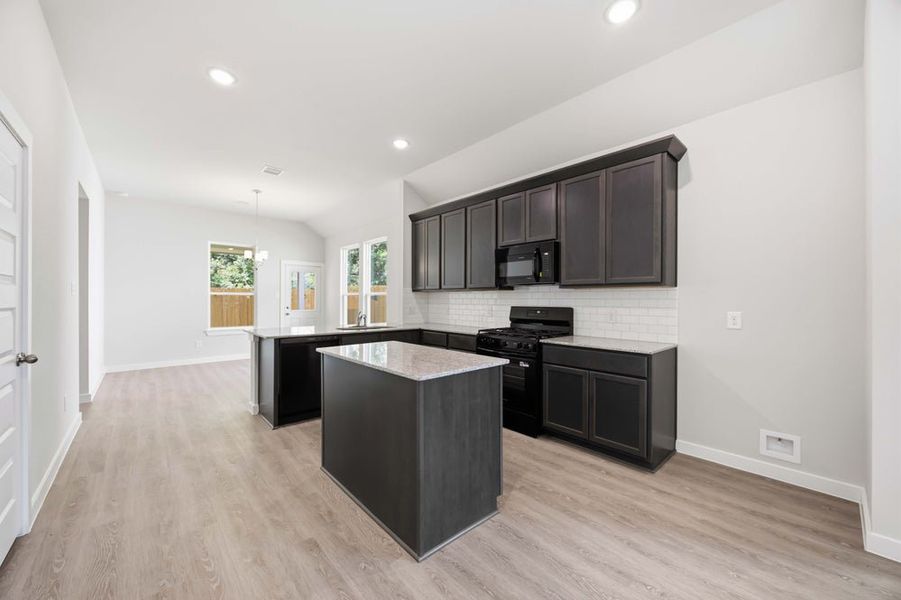 Modern kitchen with dark wood cabinets, granite countertop island, black appliances, and hardwood flooring Modern kitchen with dark wood cabinets, granite countertop island, black appliances, and hardwood flooring