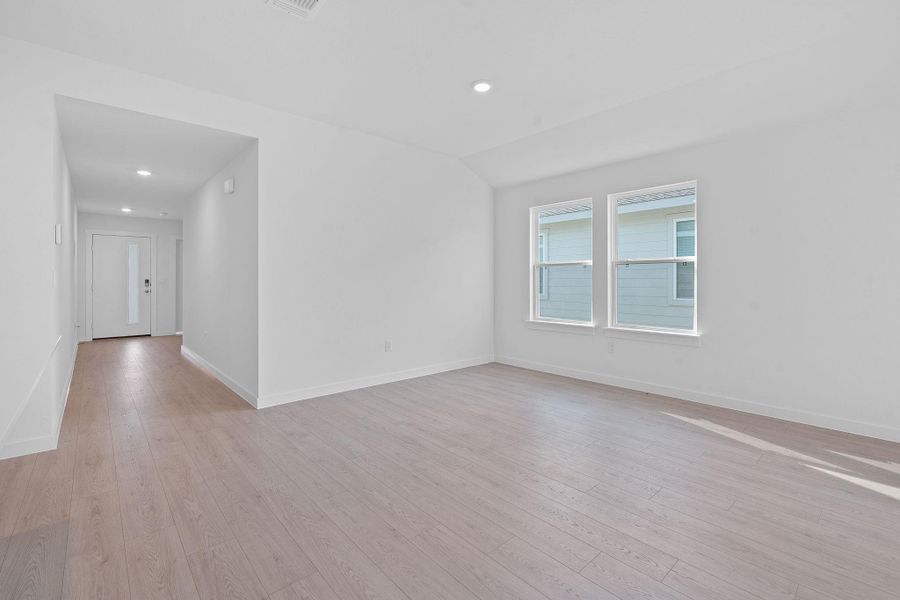 Empty room with light wood-style floors, recessed lighting, and lofted ceiling