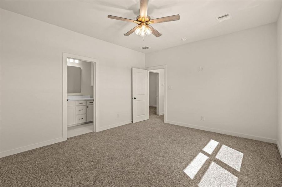 Unfurnished bedroom featuring light colored carpet, baseboards, ensuite bathroom, and ceiling fan
