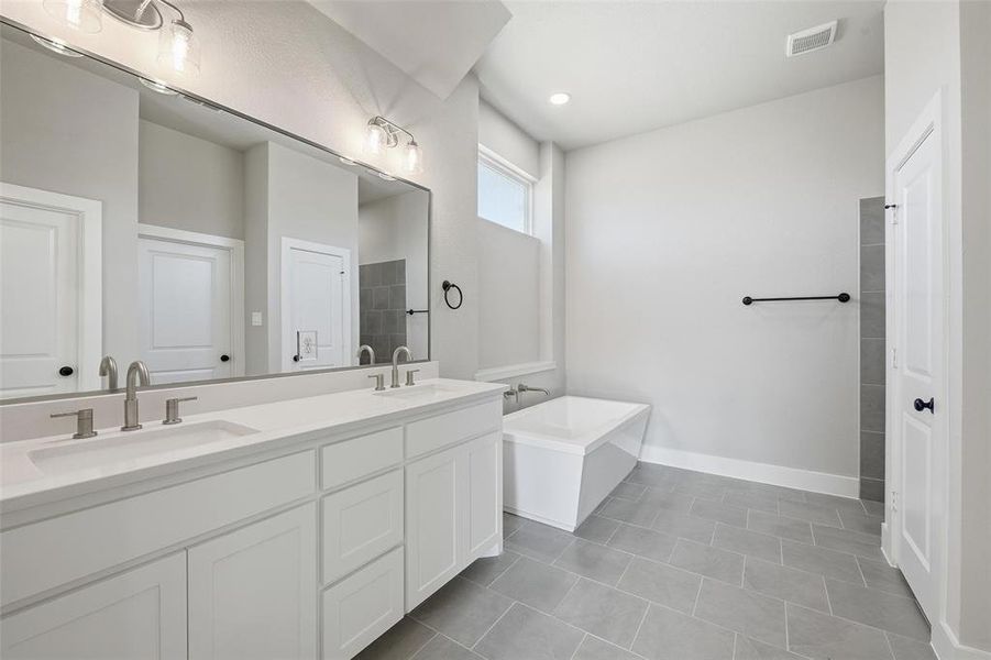 Bathroom featuring a tub, double vanity, and light tile patterned floors Bathroom featuring a tub, double vanity, and light tile patterned floors