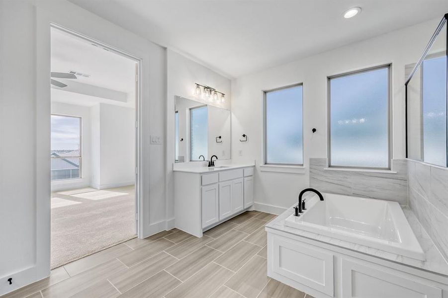 Full bath with a bath, vanity, healthy amount of natural light, and wood finish floors
