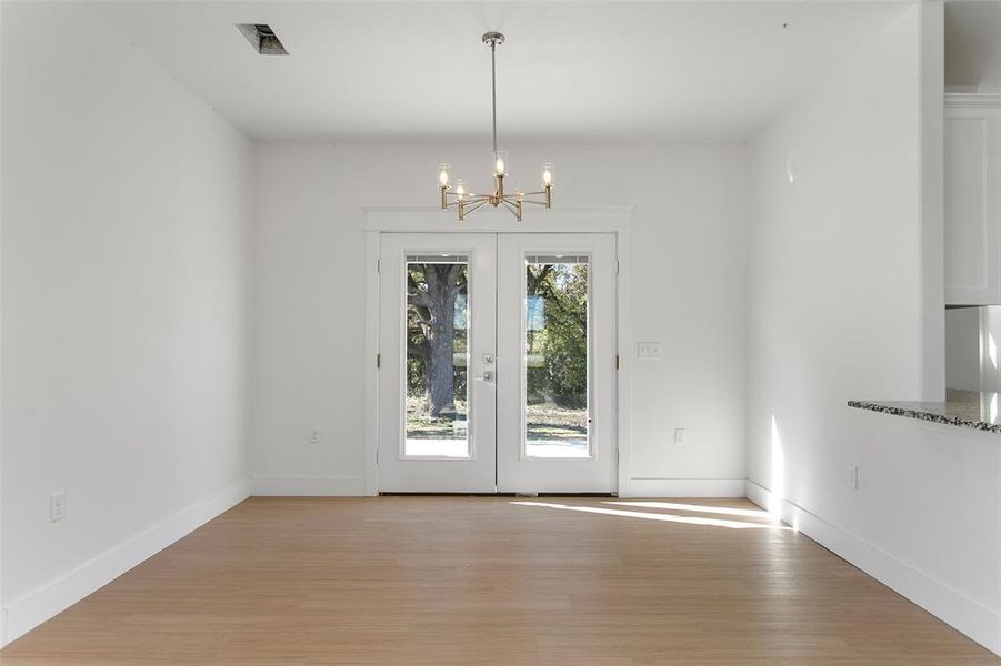 Unfurnished dining area featuring a notable chandelier and light hardwood / wood-style flooring