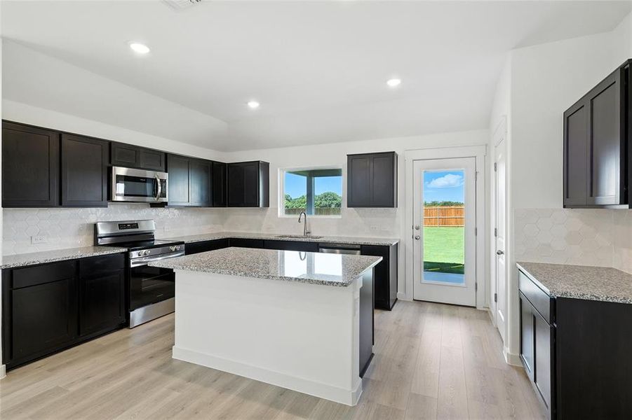Kitchen with backsplash, stainless steel appliances, light stone counters, and recessed lighting Kitchen with backsplash, stainless steel appliances, light stone counters, and recessed lighting