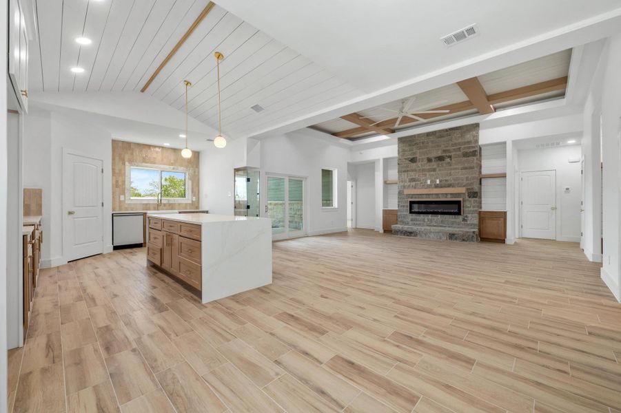 Kitchen featuring open floor plan, wood tiled floors, decorative light fixtures, a fireplace, and a center island Kitchen featuring open floor plan, wood tiled floors, decorative light fixtures, a fireplace, and a center island