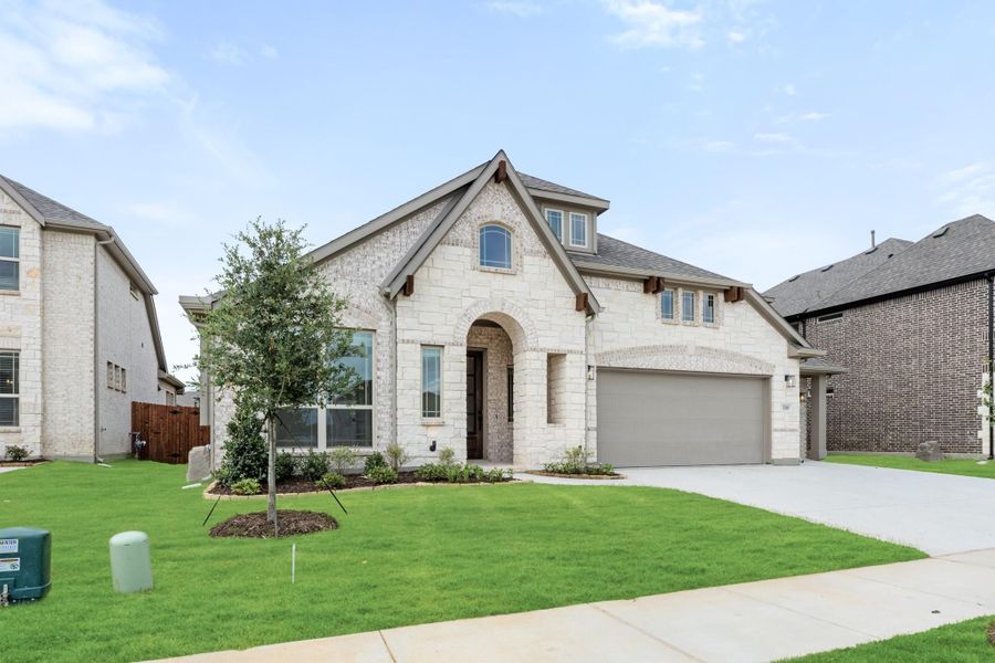 Two-story home with light stone exterior, arched entry, two-car garage, and manicured front lawn Two-story home with light stone exterior, arched entry, two-car garage, and manicured front lawn