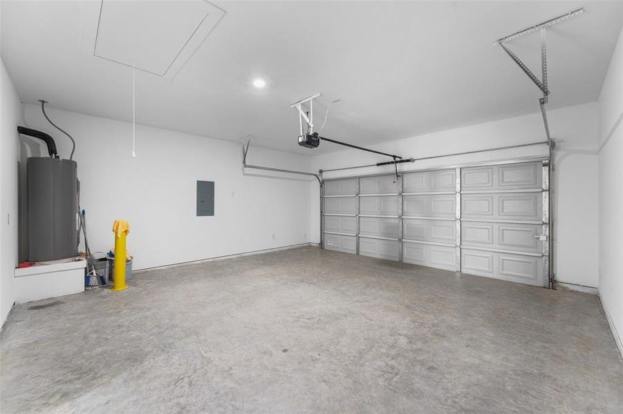 Attached two-car garage with a panel garage door, concrete flooring, and an overhead garage door opener