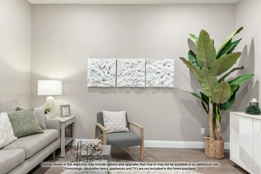Living room with gray sofa, accent chair, white wall art panels, and large potted plant on hardwood floors