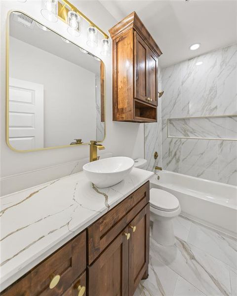 Bathroom featuring vanity, light marble finish floors, and tub / shower combination