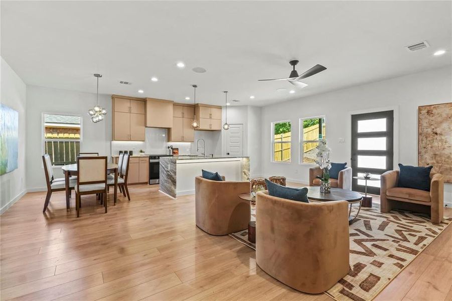 Living room featuring plenty of natural light, recessed lighting, light wood-style flooring, a chandelier, and ceiling fan Living room featuring plenty of natural light, recessed lighting, light wood-style flooring, a chandelier, and ceiling fan