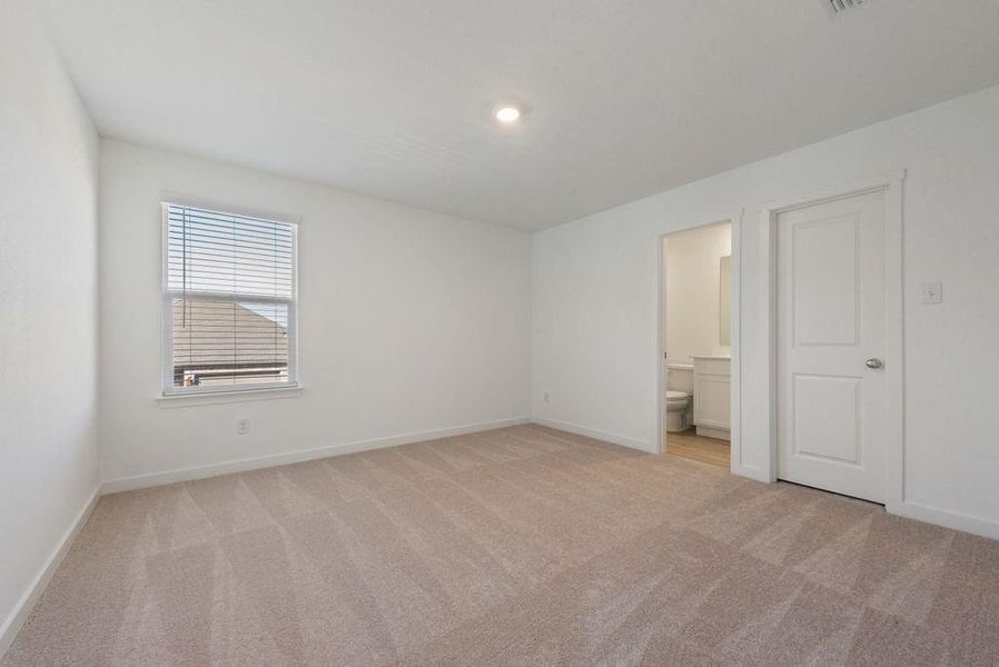Unfurnished bedroom featuring light colored carpet and connected bathroom Unfurnished bedroom featuring light colored carpet and connected bathroom