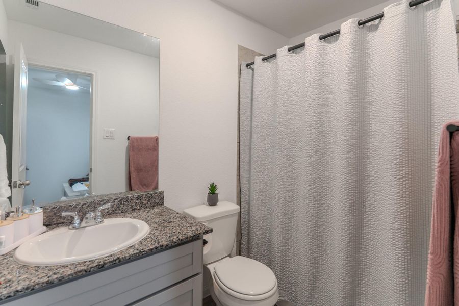 Ensuite primary bath with walk-in shower and granite countertops Ensuite primary bath with walk-in shower and granite countertops