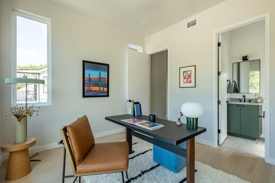 An inviting home workspace opens directly to a modern private bathroom. An inviting home workspace opens directly to a modern private bathroom.