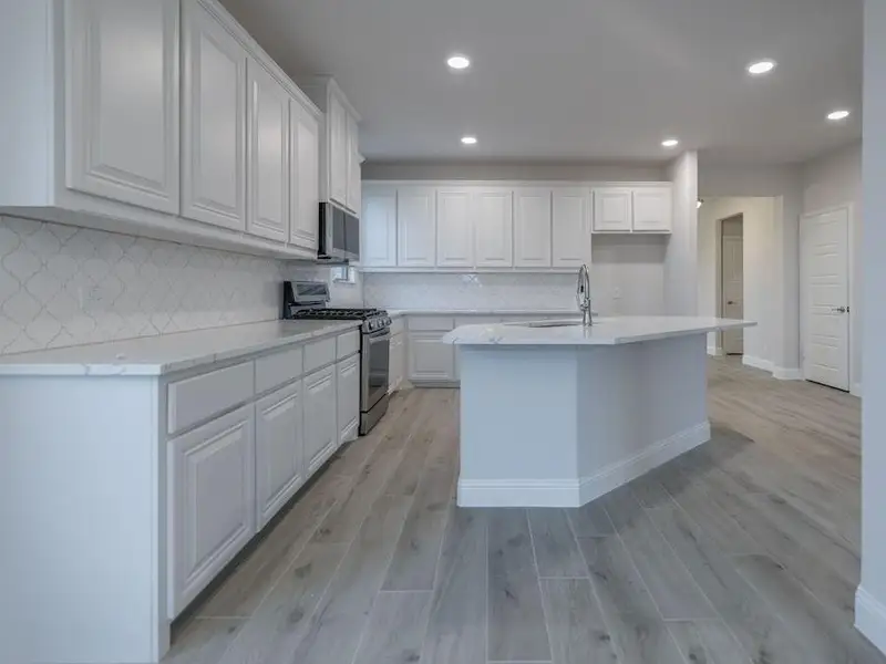 Kitchen featuring backsplash, white cabinets, light wood-type flooring, and appliances with stainless steel finishes