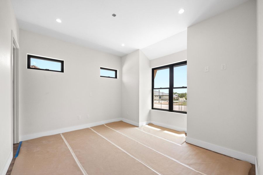 Bright room featuring a large black-framed window and two transom windows, recessed lighting, and white baseboards