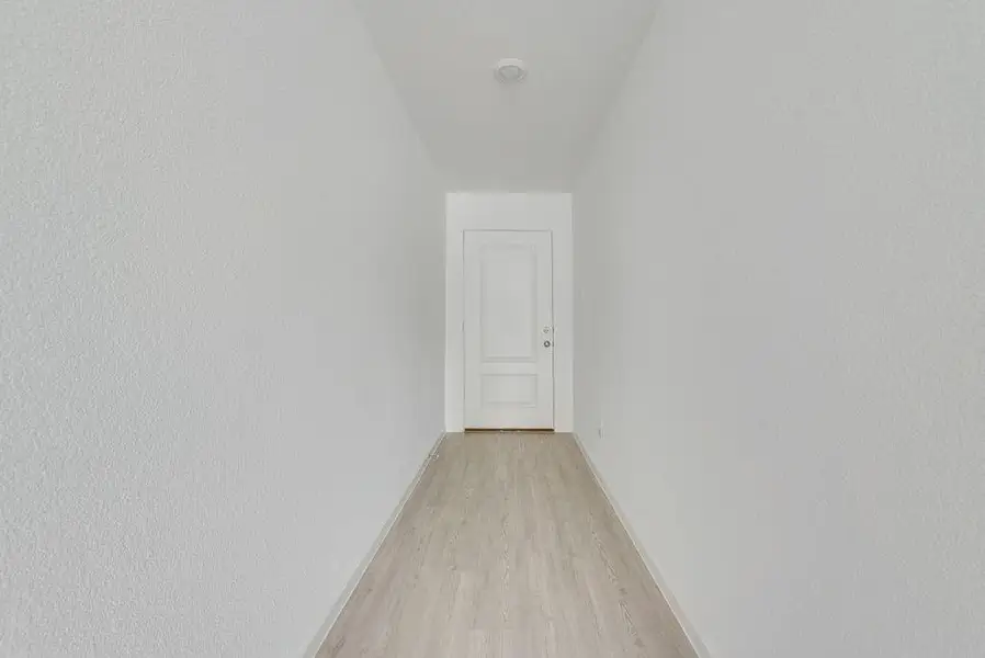 Corridor featuring light wood finished floors and baseboards Corridor featuring light wood finished floors and baseboards