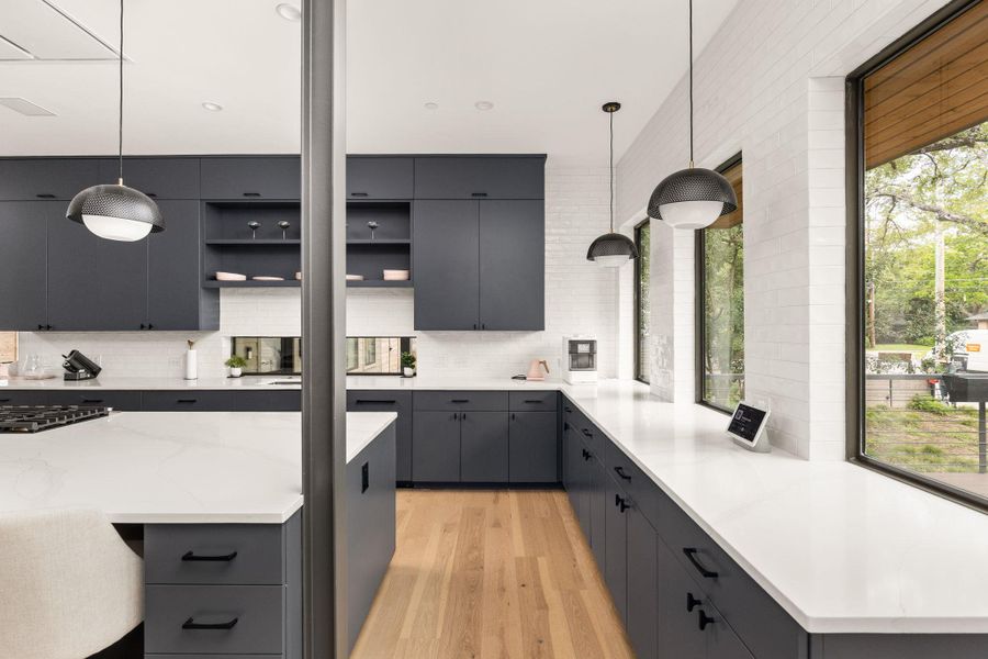 A contemporary kitchen features sleek dark cabinetry, light countertops, and abundant natural light. A contemporary kitchen features sleek dark cabinetry, light countertops, and abundant natural light.