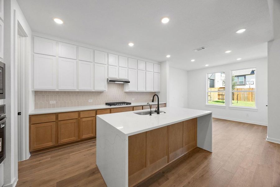 Kitchen featuring backsplash, light stone countertops, light wood finished floors, and recessed lighting Kitchen featuring backsplash, light stone countertops, light wood finished floors, and recessed lighting