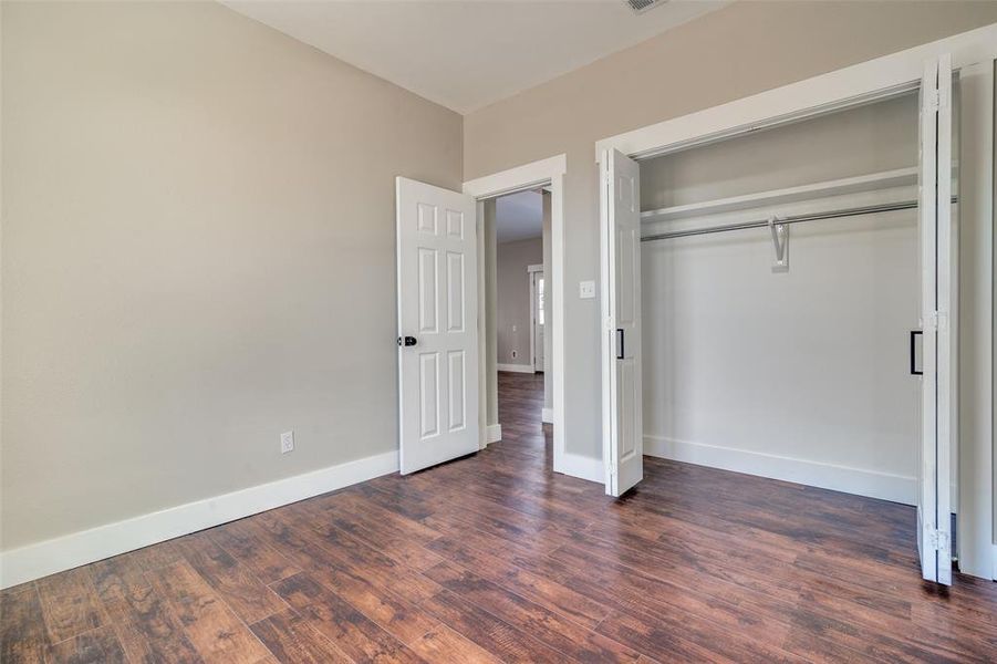 Unfurnished bedroom with dark hardwood / wood-style flooring and a closet