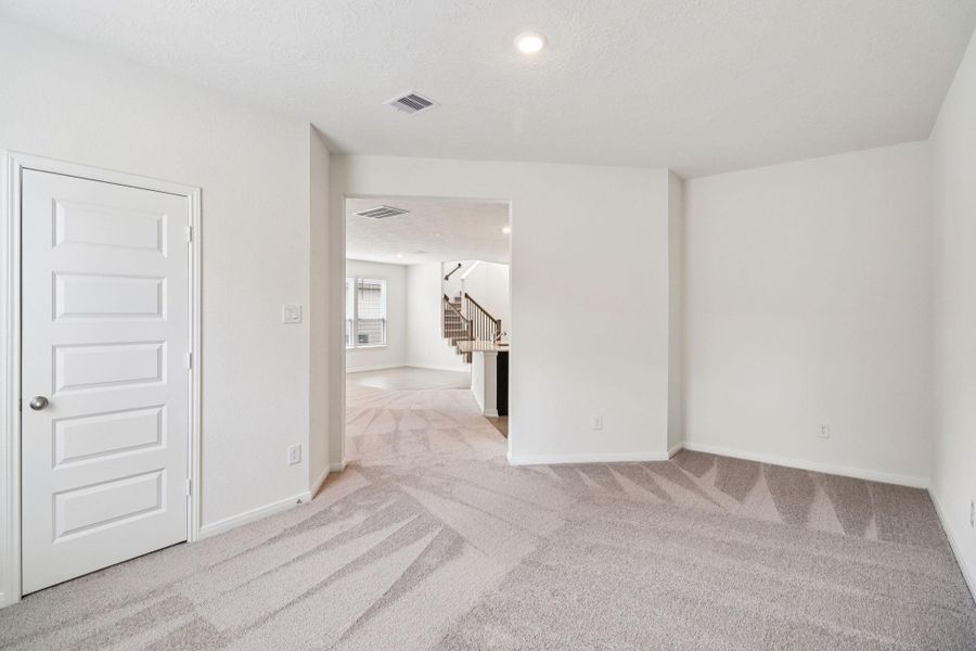 The Den features custom neutral paint, recessed lighting, large window with blinds, closet space, and the continuous flow of the carpet flooring.