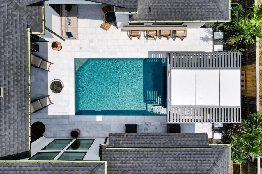 Overhead view of the pool, spa, and bar. The entire deck is done in gorgeous white travertine. Behind the spa, there is a shower, a bench, and a place to hang everyone's towels.