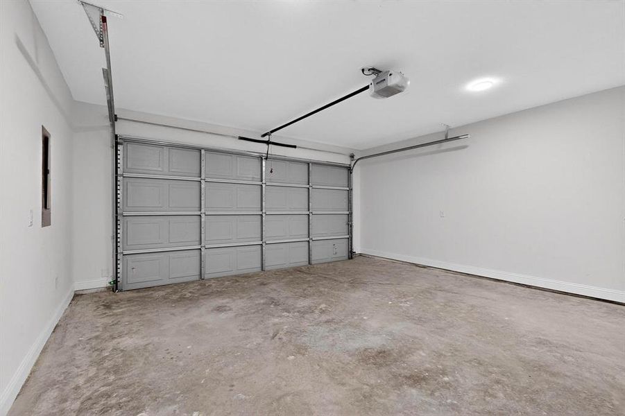 Garage with baseboards and a garage door opener Garage with baseboards and a garage door opener