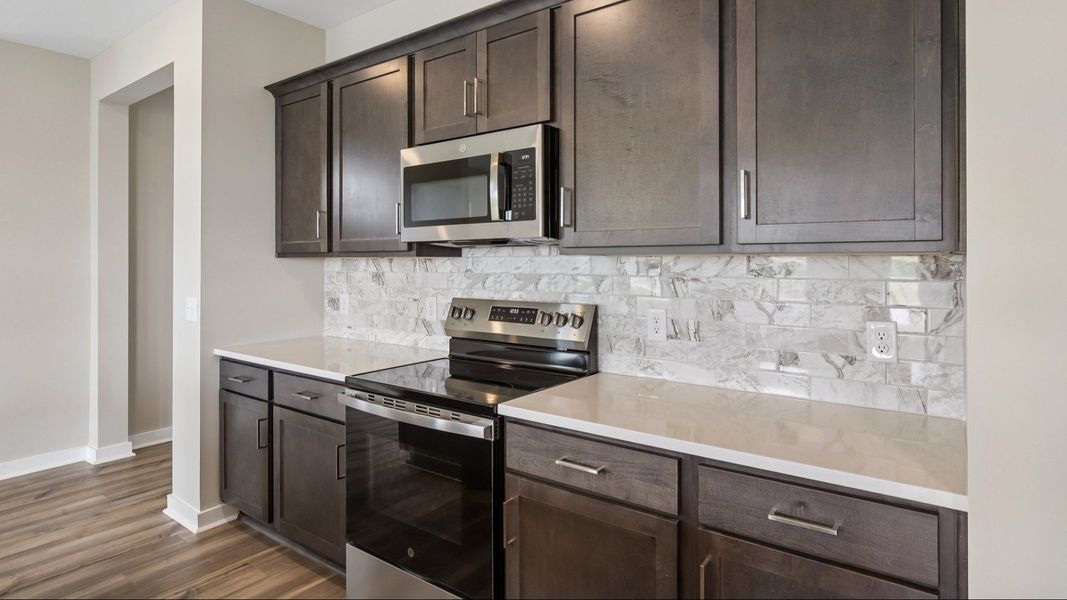 Kitchen with dark cabinetry, quartz countertops, and tile backsplash