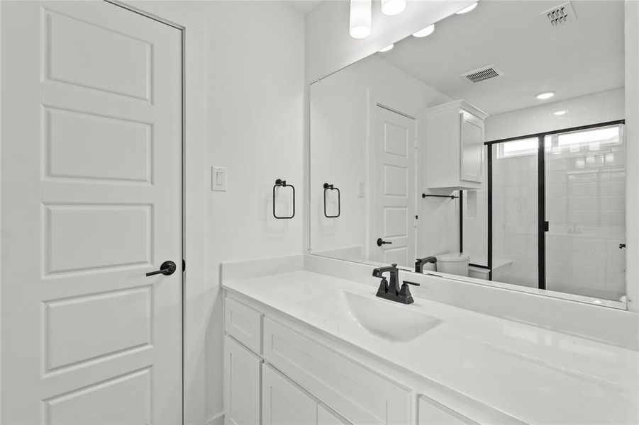 Bathroom with vanity, toilet, and a shower with shower door