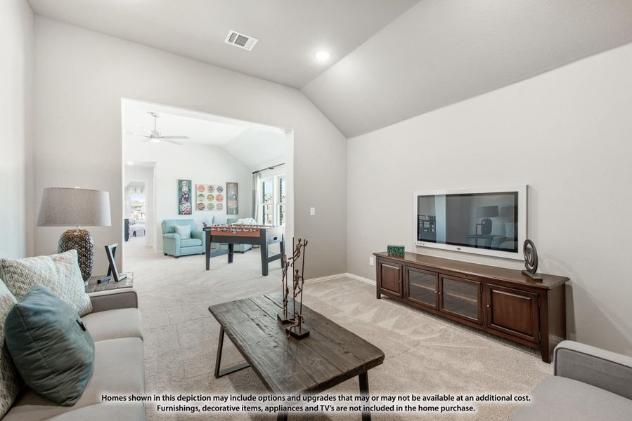Living room with vaulted ceiling, wall-mounted TV, and open view into game room with foosball table Living room with vaulted ceiling, wall-mounted TV, and open view into game room with foosball table