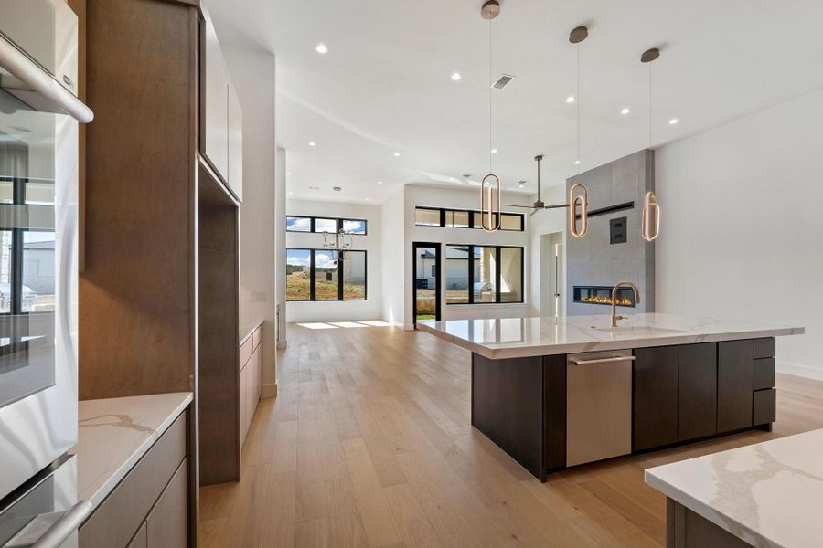 Kitchen featuring modern cabinets, pendant lighting, light wood-style flooring, light stone countertops, and a high ceiling
