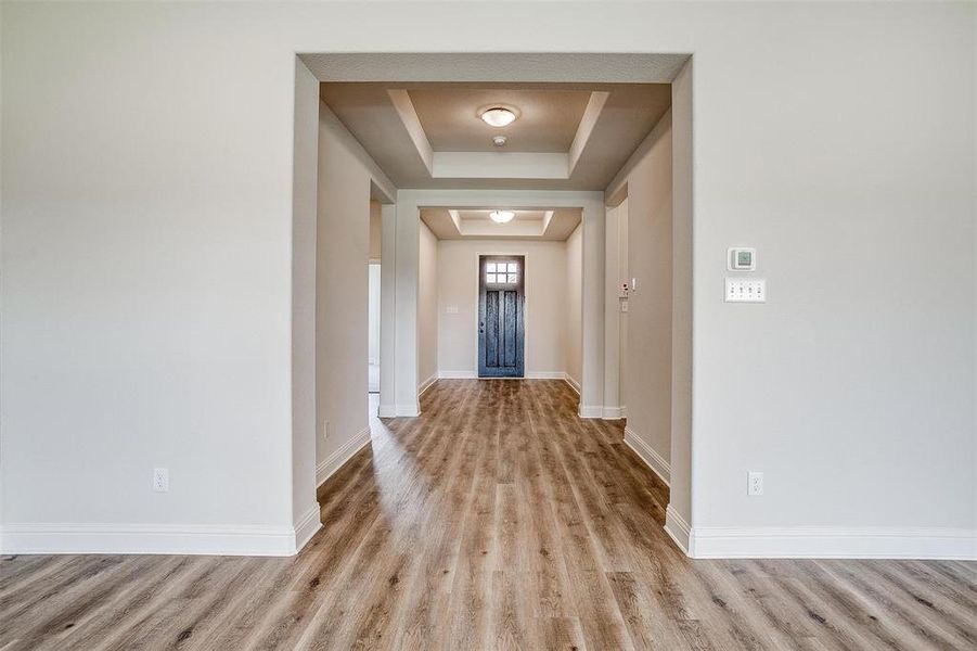 Corridor featuring wood-type flooring and a tray ceiling