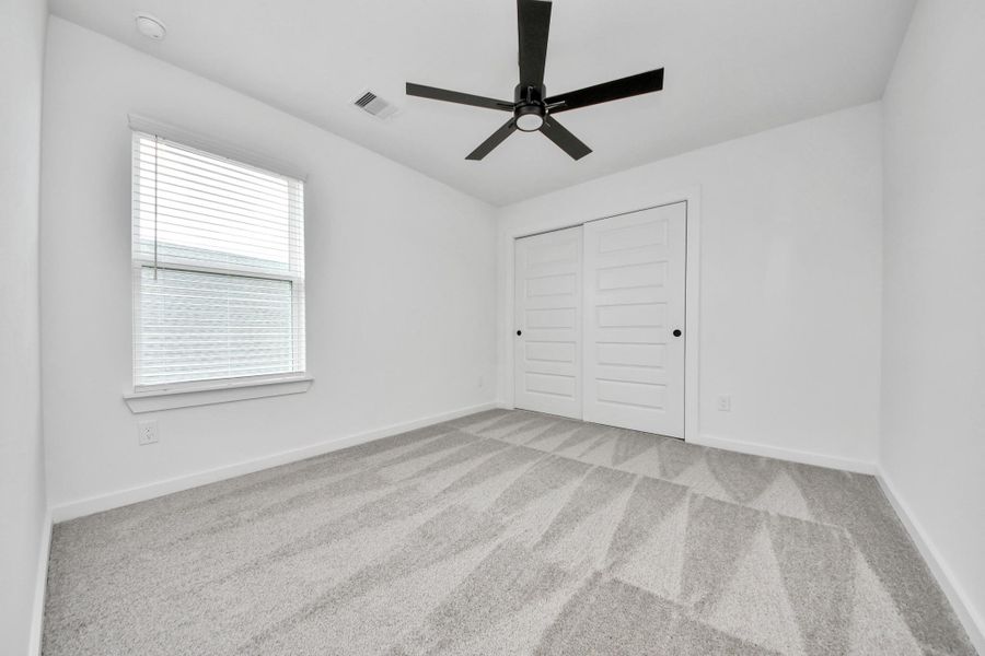 Secondary bedroom features plush carpeting, large windows that let in plenty of natural light, bright paint, and spacious closets. Sample photo of completed home with similar floor plan. Actual colors and selections may vary. Secondary bedroom features plush carpeting, large windows that let in plenty of natural light, bright paint, and spacious closets. Sample photo of completed home with similar floor plan. Actual colors and selections may vary.