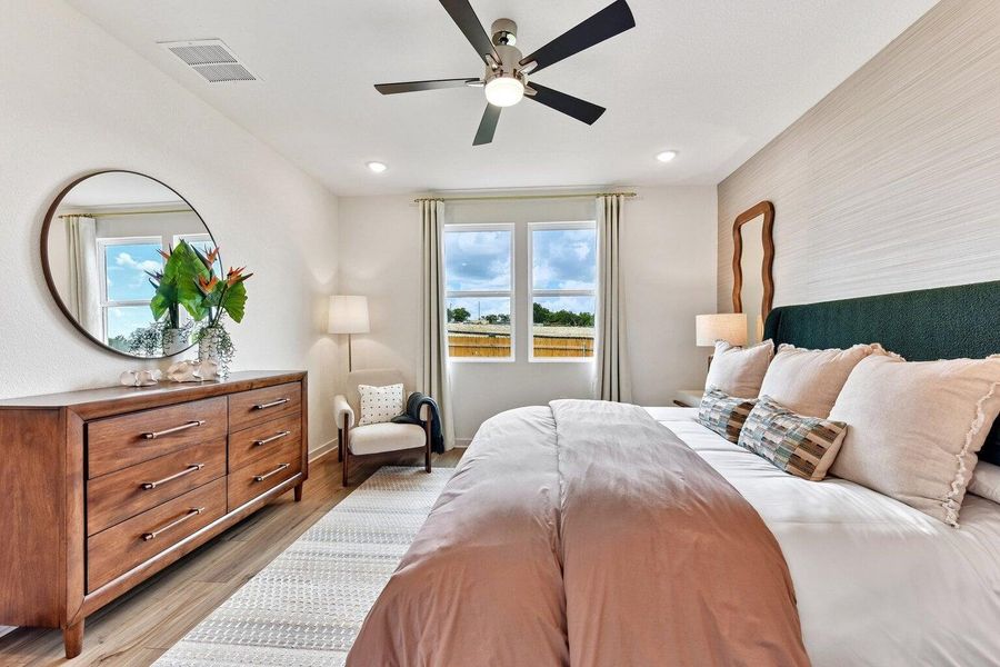 Well-lit bedroom features ample natural light and a contemporary ceiling fan, providing comfort and style.