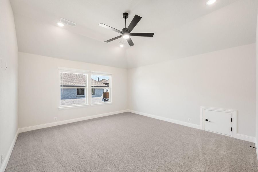 Empty bedroom with gray carpet, vaulted ceiling, black ceiling fan, and a single window