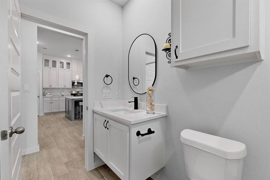 Half bathroom featuring vanity and light wood-style floors Half bathroom featuring vanity and light wood-style floors