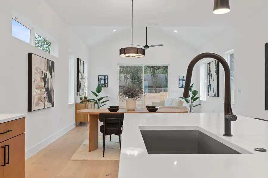 Kitchen with decorative light fixtures, light wood-type flooring, light stone countertops, recessed lighting, and high vaulted ceiling Kitchen with decorative light fixtures, light wood-type flooring, light stone countertops, recessed lighting, and high vaulted ceiling