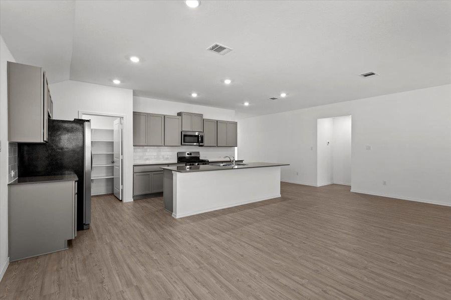 A well-lit, open-concept kitchen and living area features sleek cabinetry and durable plank flooring. A well-lit, open-concept kitchen and living area features sleek cabinetry and durable plank flooring.