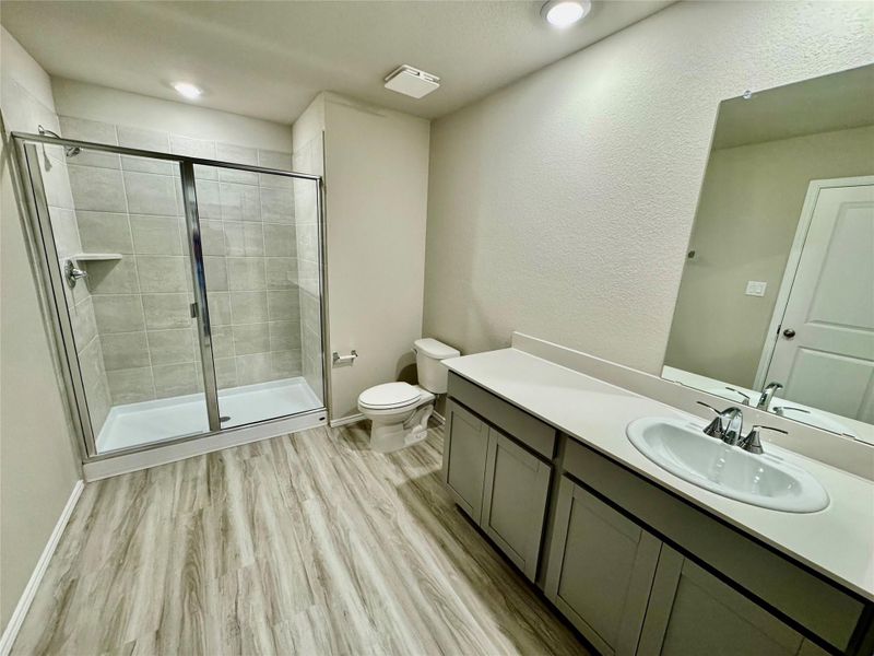 Bathroom with a stall shower, vanity, light wood-type flooring, a textured wall, and recessed lighting