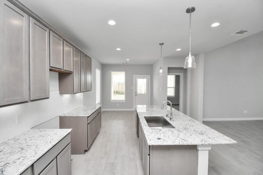 This generously spacious kitchen is a dream realized! With a massive granite island, high ceilings, soft close cabinets, granite countertops, stainless steel appliances, a sleek tile backsplash, recessed lighting, and an extended counter area, it offers both style and practicality. All this opens up to the expansive family room, creating a perfect hub for gatherings. Sample photo of completed home with similar floor plan. Actual colors and selections may vary. This generously spacious kitchen is a dream realized! With a massive granite island, high ceilings, soft close cabinets, granite countertops, stainless steel appliances, a sleek tile backsplash, recessed lighting, and an extended counter area, it offers both style and practicality. All this opens up to the expansive family room, creating a perfect hub for gatherings. Sample photo of completed home with similar floor plan. Actual colors and selections may vary.